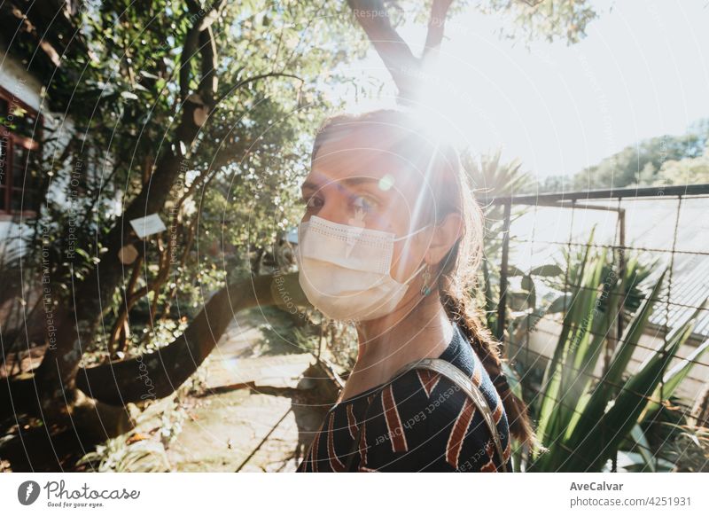Woman using a mask looking straight to camera during a bright sunset in a garden person female holding woman hipster smile sunlight gardening happy carefree
