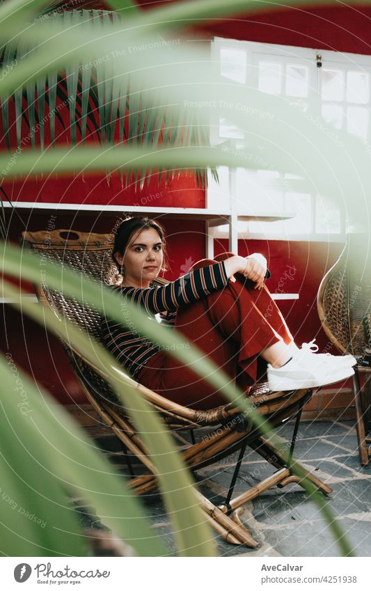 Woman sitting on a bamboo chair looking straight to camera, portrait mental health concept person female holding woman hipster smile sunlight gardening happy