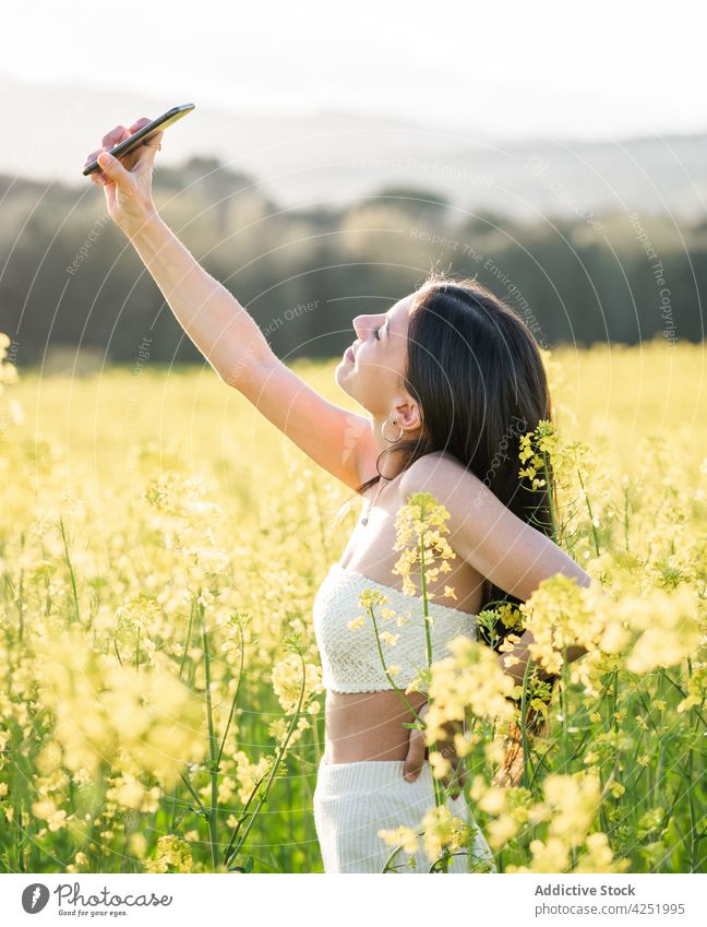 Happy woman taking selfie on blooming field content smile smartphone take photo countryside meadow flower self portrait photography moment mobile lifestyle