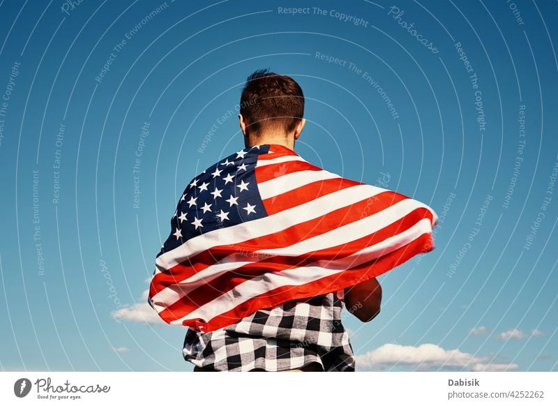 Man holds usa national flag against blue sky american outdoor man 4th july person waving people summer day stars stripes background beautiful independence