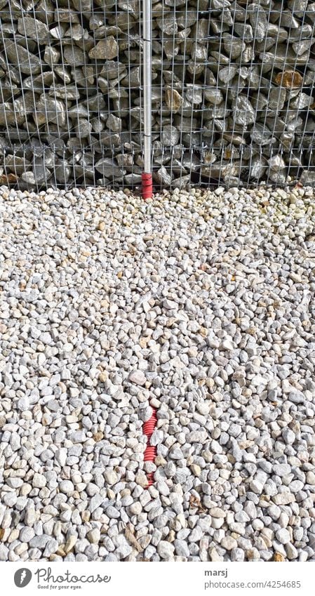 If the flex pipe wasn't red, the color would be gone. Gravel bed in front of bordered stone wall with red flex pipe. stones Stony Stone wall Rubble stones