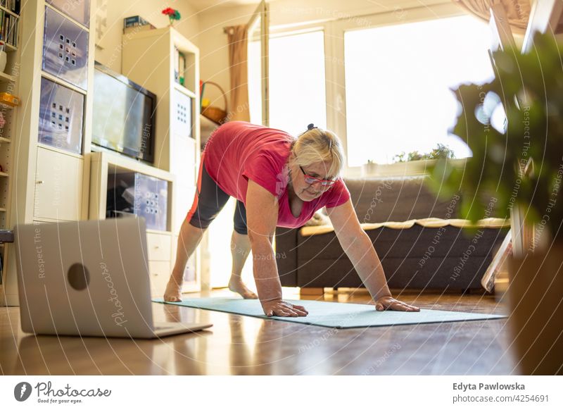 Senior woman exercising at home eyeglasses wrinkles natural real people casual day lifestyle grandmother pensioner aged leisure retirement retired one person