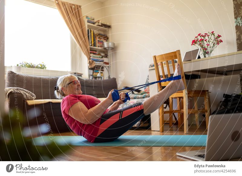 Senior woman exercising at home eyeglasses wrinkles natural real people casual day lifestyle grandmother pensioner aged leisure retirement retired one person