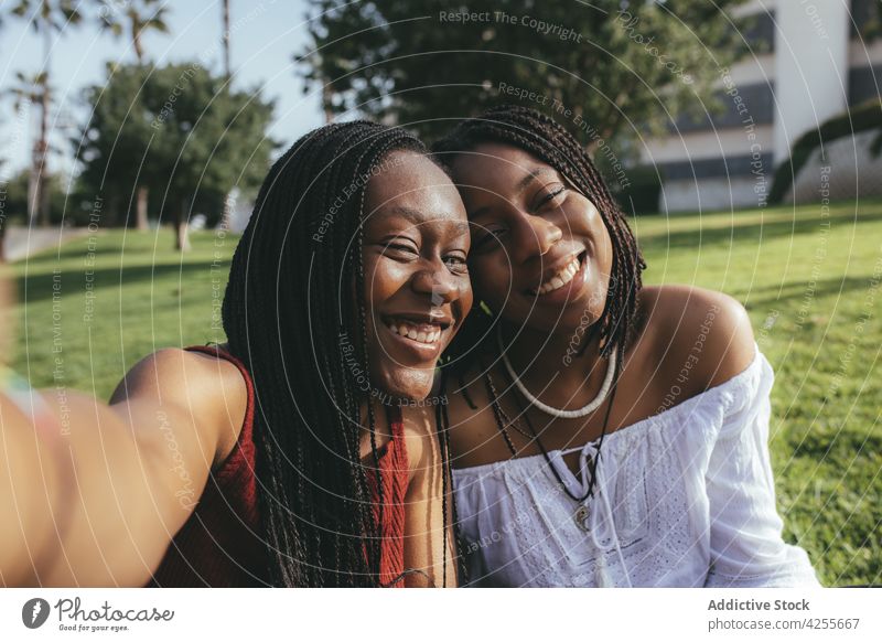 Happy black women taking selfie on lawn girlfriend self portrait smartphone friendship bonding photography best friend park street together african american