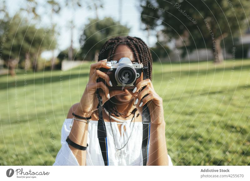 Anonymous black woman taking photo on camera photographer photo camera take photo capture memory moment lawn park photography female hobby african american
