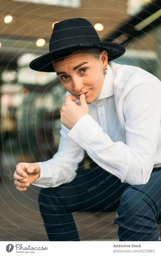Stylish tomboy in hat smoking cigarette woman smoker habit negative style eccentric queer masculine female transgender agender provocative alternative rebel