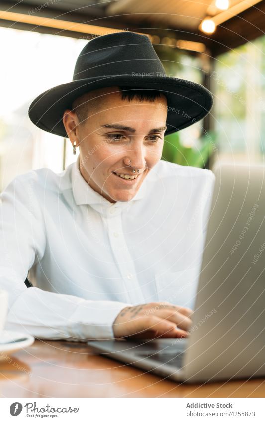 Stylish tomboy typing on laptop while working in cafe woman using freelance queer masculine browsing remote female surfing device netbook internet focus