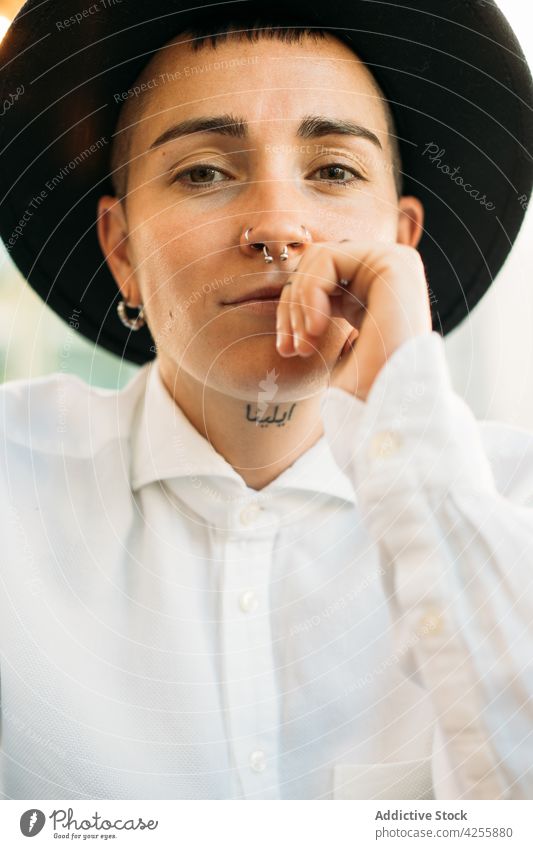 Stylish tomboy with piercing in hat woman queer eccentric transgender gaze neutral extraordinary style identity female unique agender table serious unusual