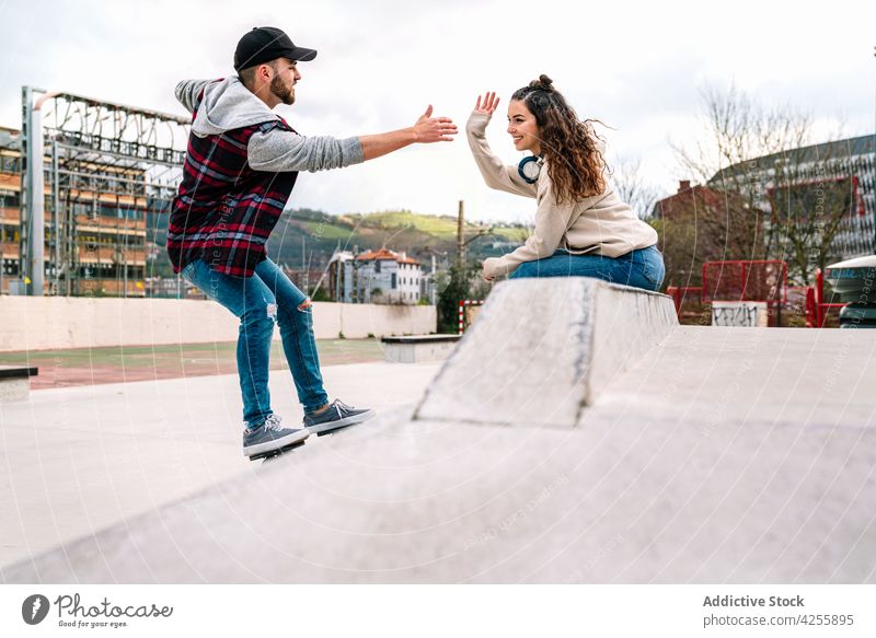 Man giving five to woman while practicing on freeline skates cheerful friend smile practice drift together activity energy stunt extreme urban ramp skate park