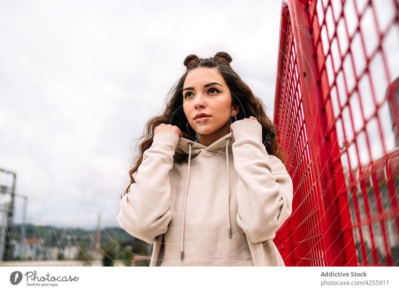 Woman with piercing and buns on head in hoodie woman urban street millennial carefree appearance town outfit modern female young pink wavy hair contemporary