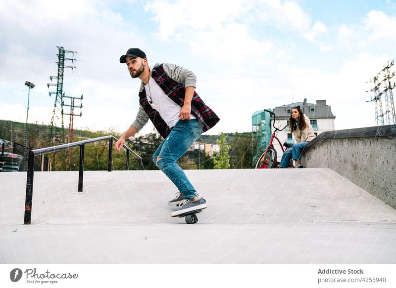 Man near woman while practicing on freeline skates cheerful friend smile practice drift together activity energy stunt extreme urban ramp skate park millennial