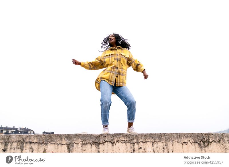 Energetic black woman dancing on concrete border carefree shake dance move leisure freestyle dynamic motion enjoy female action posture millennial smile
