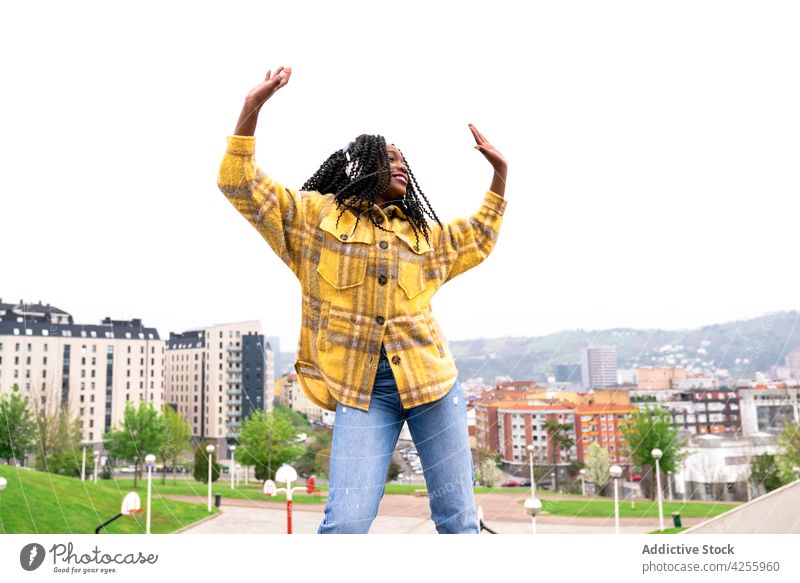 Energetic black woman dancing with the city in the background headphones listening carefree shake dance move leisure music freestyle dynamic motion enjoy female