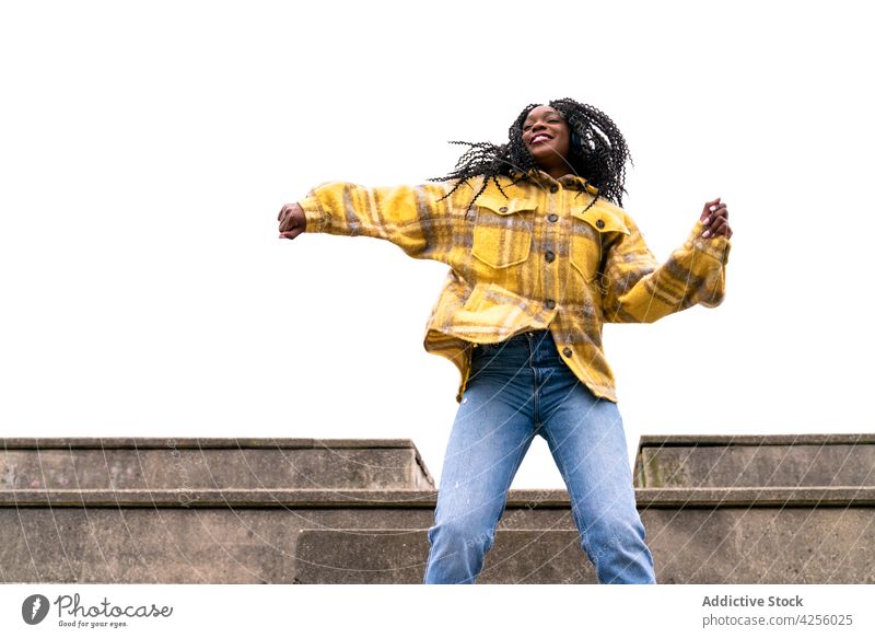 Energetic black woman dancing on concrete border carefree shake dance move leisure freestyle dynamic motion enjoy female action posture millennial smile