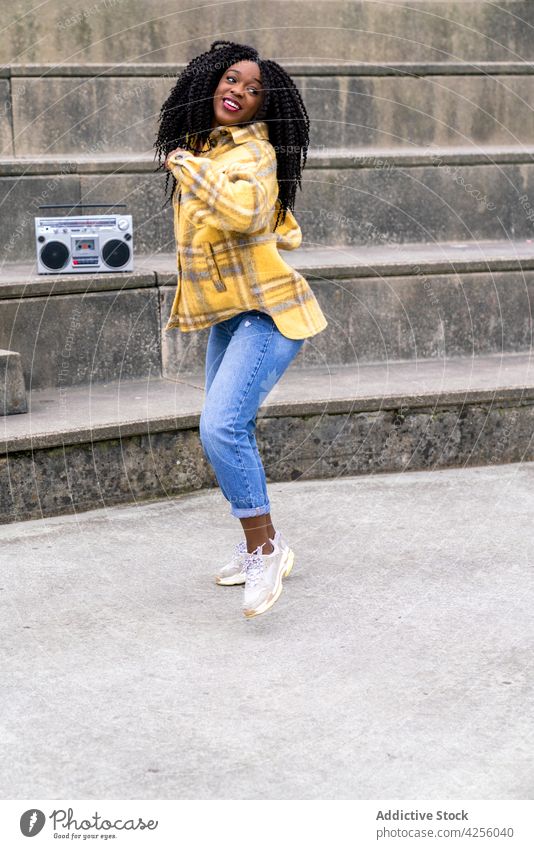 Black woman listening to music and dancing enjoy song boombox entertain cool positive female blaster portable retro old fashioned cheerful casual young