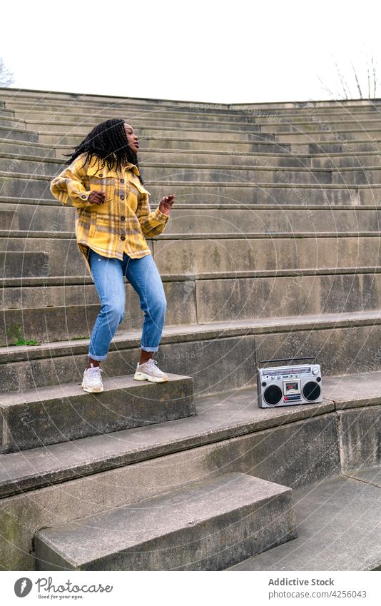 Black woman listening to music and dancing enjoy song boombox entertain cool positive female blaster portable retro old fashioned cheerful casual young