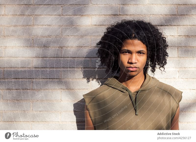 Serious black curly haired man standing in sunlight teenage millennial cool youngster carefree serious afro appearance glance male personality hairstyle