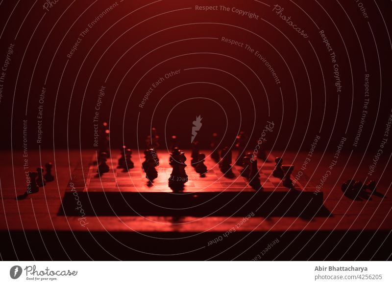 Chess board with chess pieces table still life dark shadow red light color objects halo Chessboard Playing Horse King pawn bishop Intellect Queen Colour photo