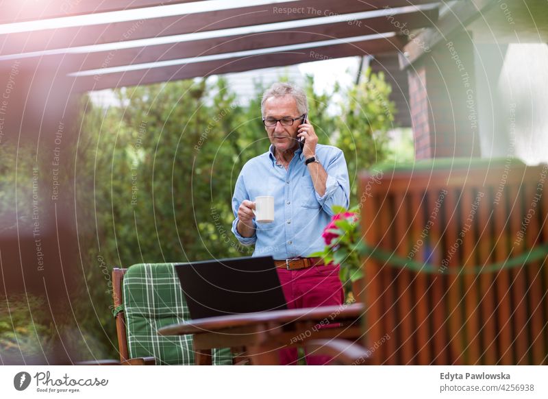Senior man using mobile phone in backyard senior old men male home house people lifestyle enjoying at home domestic life real people pensioner pensioners casual