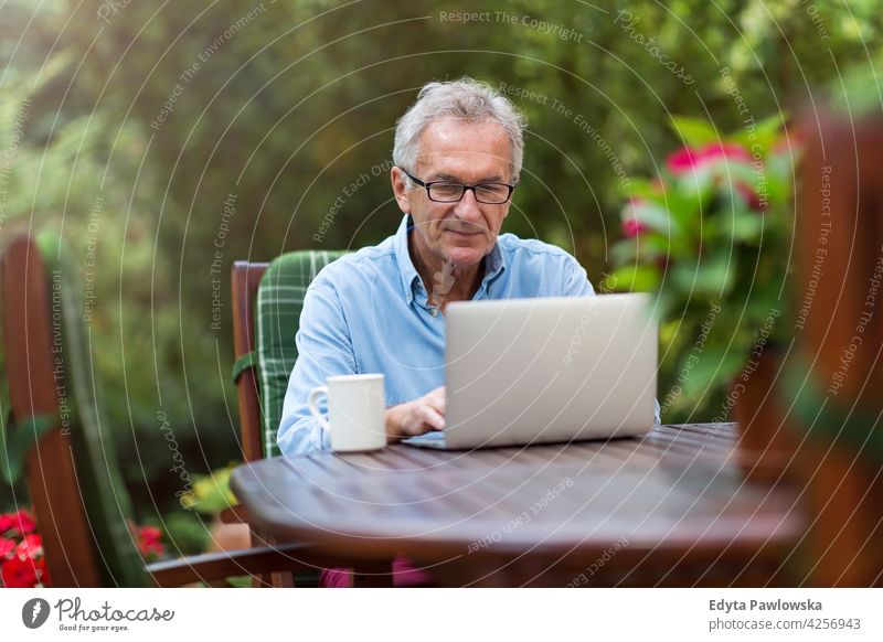 Senior man working on laptop in the garden computer technology internet using notebook senior old men male home house people lifestyle enjoying at home