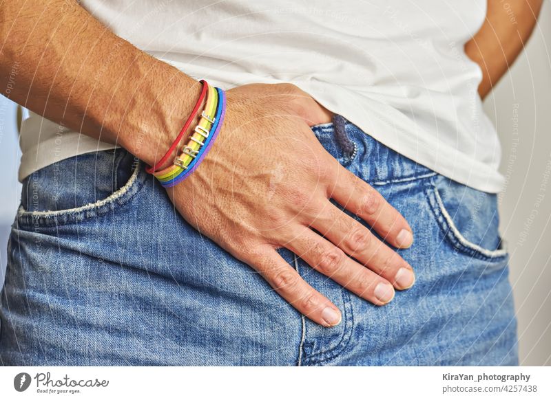 Male hand with rainbow bracelet and text pride in pocket of jeans pride month lgbt equality jeans pocket pride accessories rainbow colors awareness