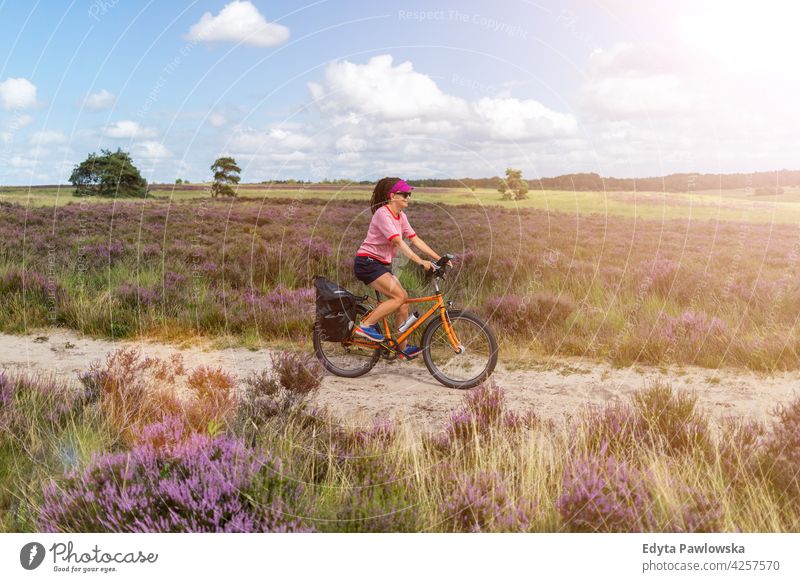 Young woman riding bicycle in the countryside, Hoge Veluwe, Holland people biking cycling bike Culture Dutch Europe Netherlands Outdoor nature sky grass field