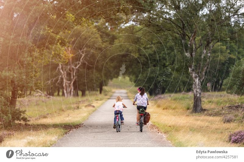 Mother and daughter cycling together in the forest family safety people girls children kids biking bike cycle Culture Dutch Europe Holland Netherlands Outdoor