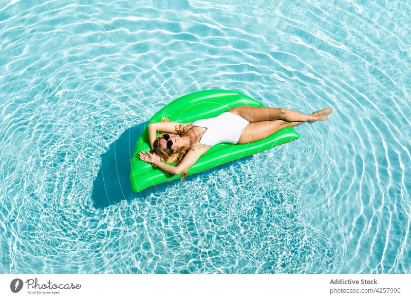 Attractive cheerful woman floating on air mattress on pool chill swimwear toothy smile sunbath suntan paradise resort inflatable swimsuit lying slim carefree