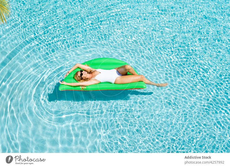 Attractive cheerful woman floating on air mattress on pool chill swimwear sunbath suntan paradise relax resort inflatable swimsuit lying slim carefree
