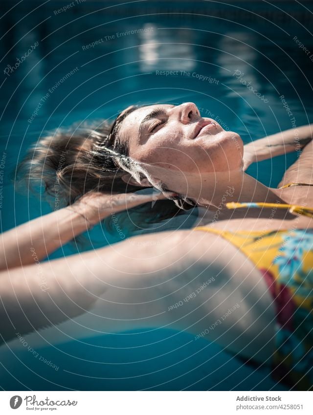 Relaxed woman floating in warm pool water chill swim swimwear eyes closed relax pleasure content feminine positive carefree together summer young resort calm