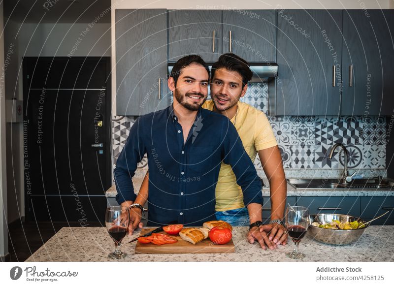 Ethnic couple of gays at kitchen table relationship love smile culinary food sincere homosexual portrait men lgbt romantic boyfriend friendly salad delicious