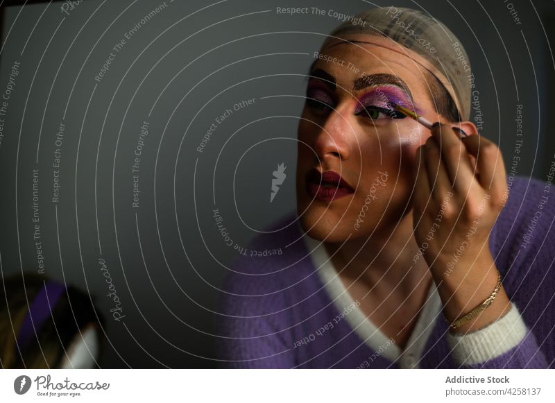 Feminine man applying makeup in dressing room androgynous feminine drag queen queer visage eccentric cosmetic individuality style extravagant prepare brush