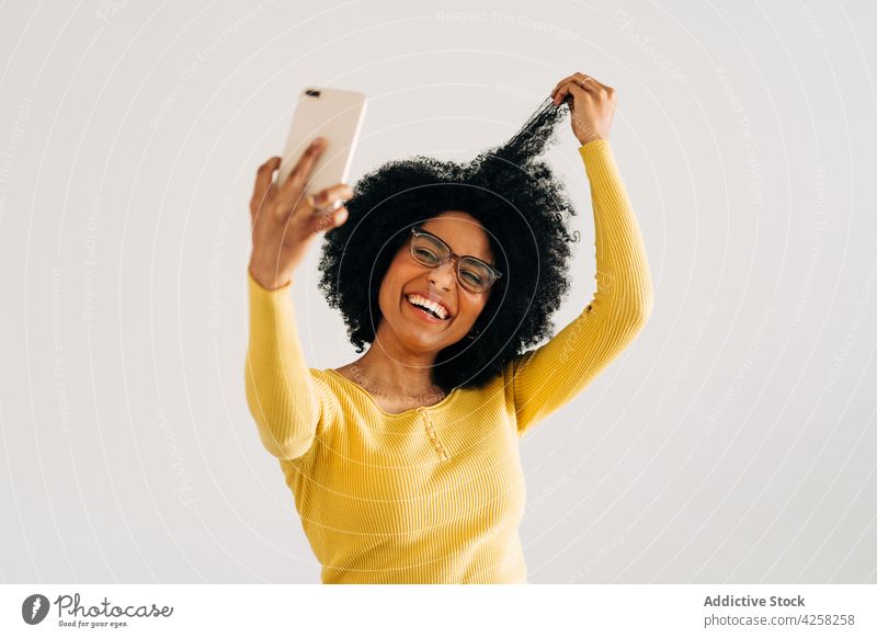 Happy black woman in eyeglasses smiling and taking selfie happy smile positive smartphone cheerful mobile carefree female yellow sweater self portrait joy afro