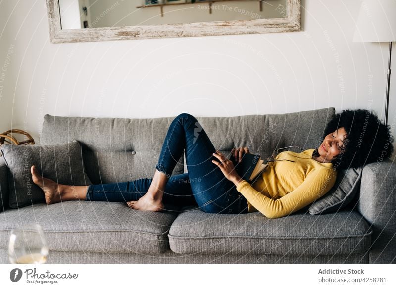 Black woman with notebook and eyeglasses resting on sofa comfort diary home couch eyes closed cozy chill asleep female black yellow sweater jeans