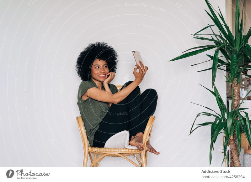 Positive black woman taking selfie near green potted plants positive smile happy smartphone take photo cheerful female using social media african american