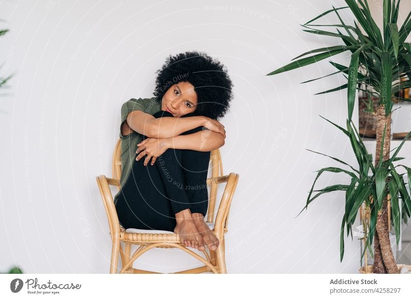 Black woman leaning chin on hands on timber chair appearance positive confident smile contemporary charismatic joy female barefoot black happy lean on hand
