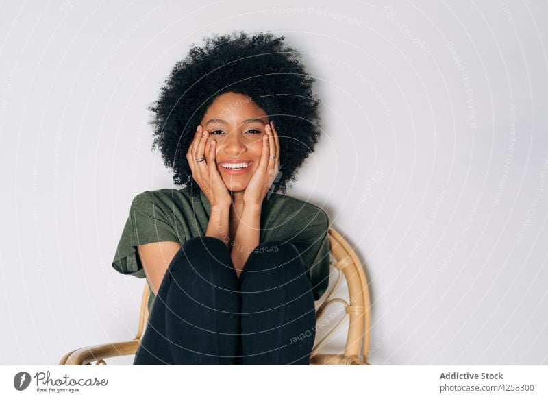 Glad black woman leaning chin on hands on timber chair appearance glad smile positive confident happy contemporary charismatic joy female lean on hand afro