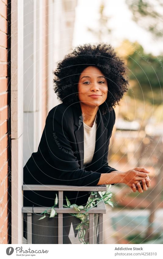 Relaxed black woman relaxing on balcony smile happy street female enjoy african american dreamy ethnic city modern afro hairstyle summer carefree urban season