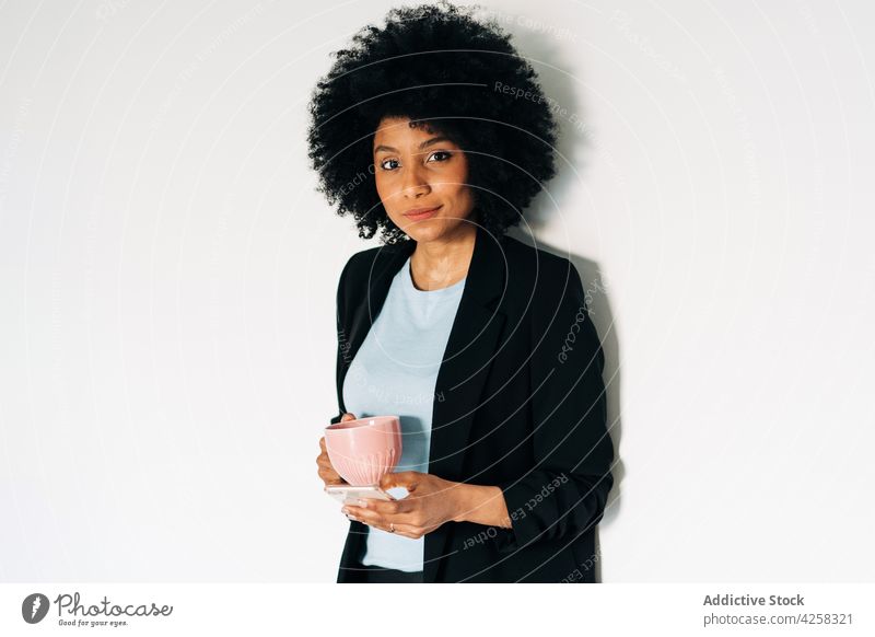 Positive black woman with cup and smartphone positive mobile elegant suit female optimist individuality mug gadget appearance formal african american lady