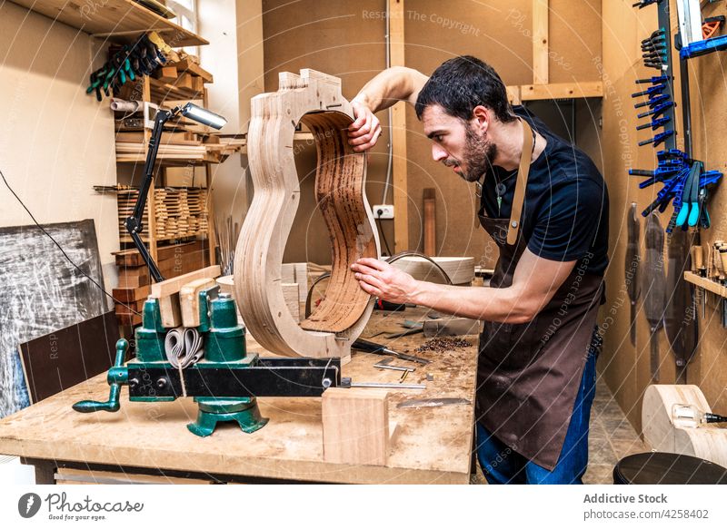 Luthier building guitar at table in workshop luthier accuracy precise profession skill man small business make musical instrument workroom clamp craftsman