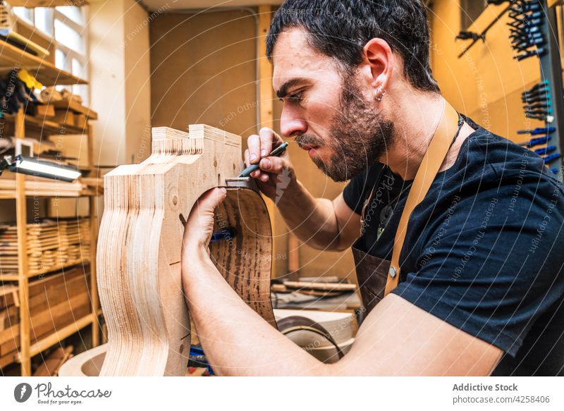 Crop luthier marking wooden piece while building guitar in workroom artisan woodwork precise accuracy focus man small business craftsmanship talent workshop