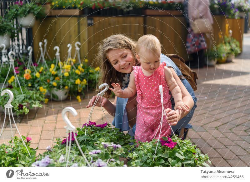 Woman with daughter choosing flowers on market woman shopping garden plant buying retail gardening gardener female young green caucasian store smiling adult