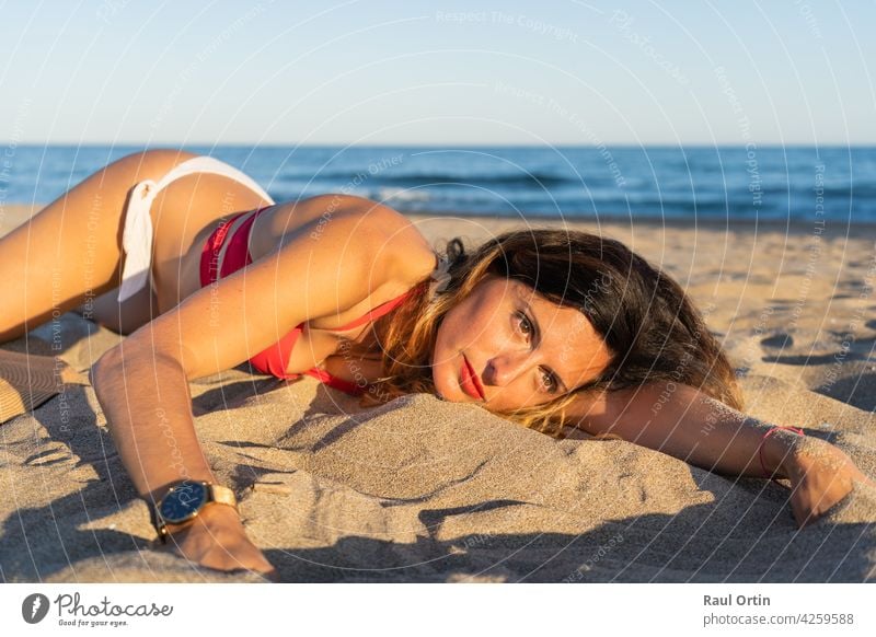 Pretty young woman lying on beach sand .Beautiful female enjoying summer sunny day .Holidays and vacation relaxation concept.Copy space. portrait holidays