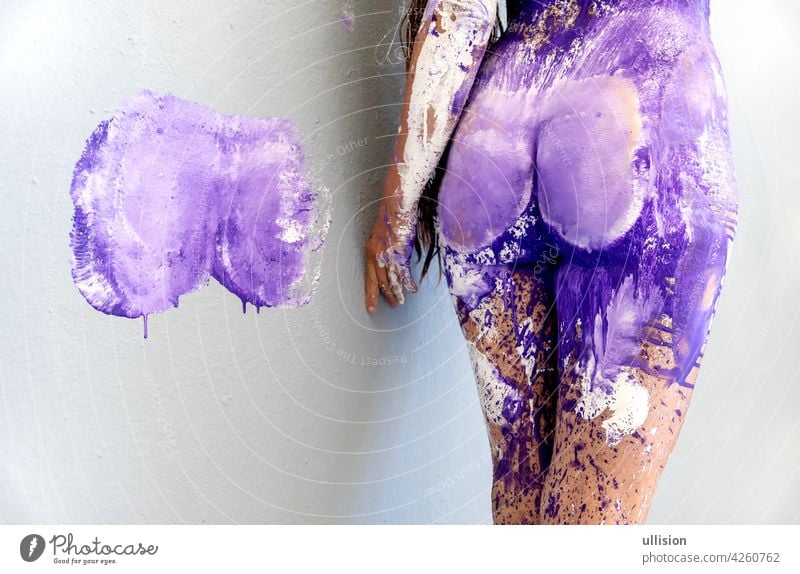 Hip buttocks and thighs of young sexy woman with color print on wall abstract bodypainting with white, purple, lilac, violet paint, creative, abstract body art,