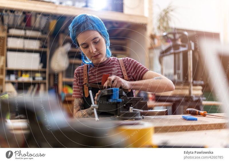 Craftswoman working in her workshop diy hipster hair tattoos female owner profession service small business employee workplace maintenance adult people expert