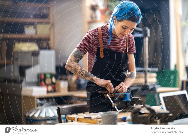 Female Carpenter In Her Workshop diy hipster hair tattoos woman female owner profession service workshop small business employee working workplace maintenance