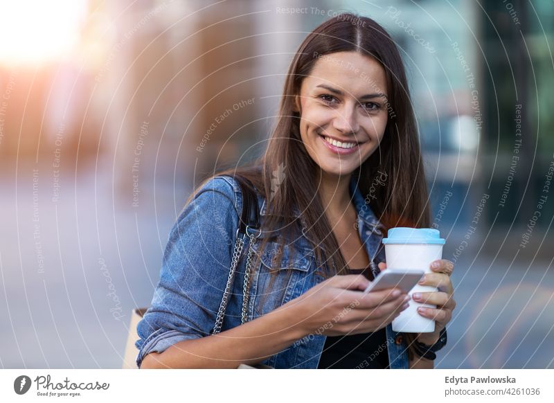 Young woman with smartphone and coffee in the city urban street active people young adult casual attractive female happy Caucasian enjoying one person beautiful
