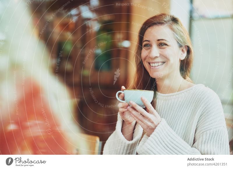 Cheerful woman talking to unrecognizable partner in cafe speak friend tea hot drink friendly spend time happy table gather beverage breakfast smile candid