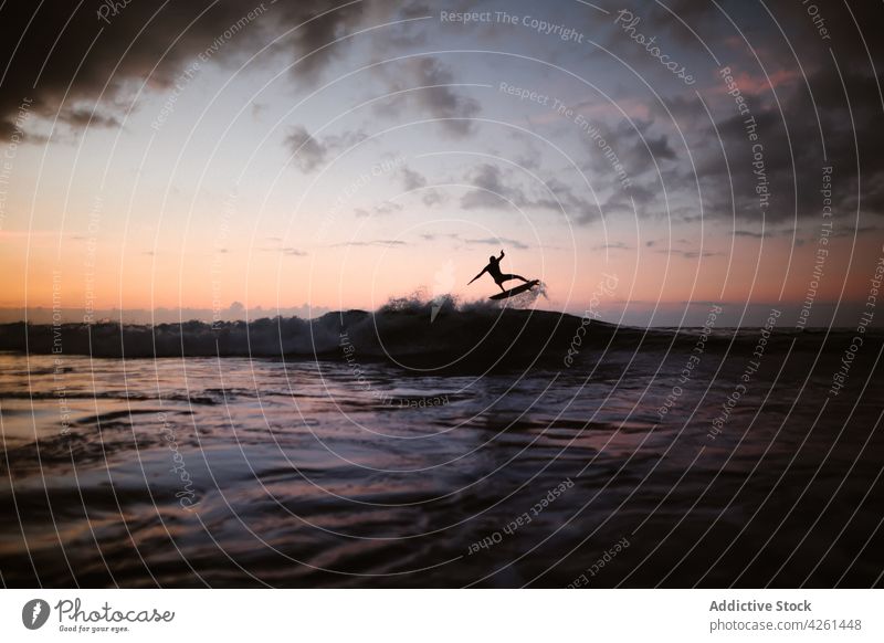 Unrecognizable athlete practicing surfing on ocean wave at sunset surfer practice sport extreme energy sea man silhouette dynamic flow fast activity brave