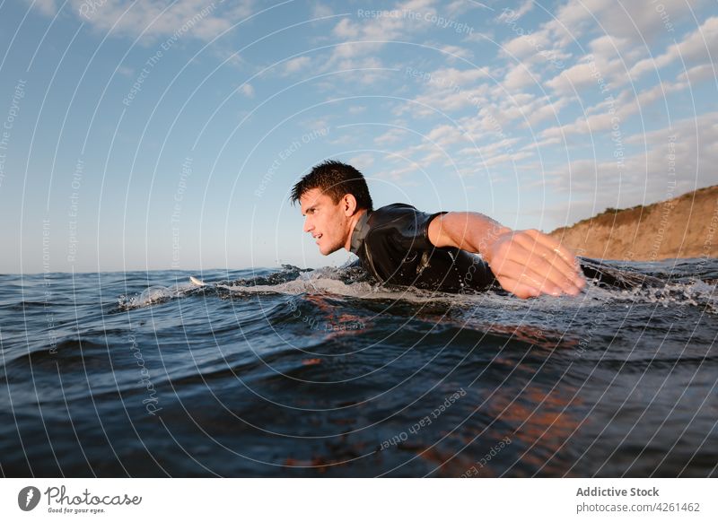 Sportsman swimming in wavy ocean against mountain athlete sea sport activity energy vitality wellness sky cloudy wetsuit sportsman practice power highland flow